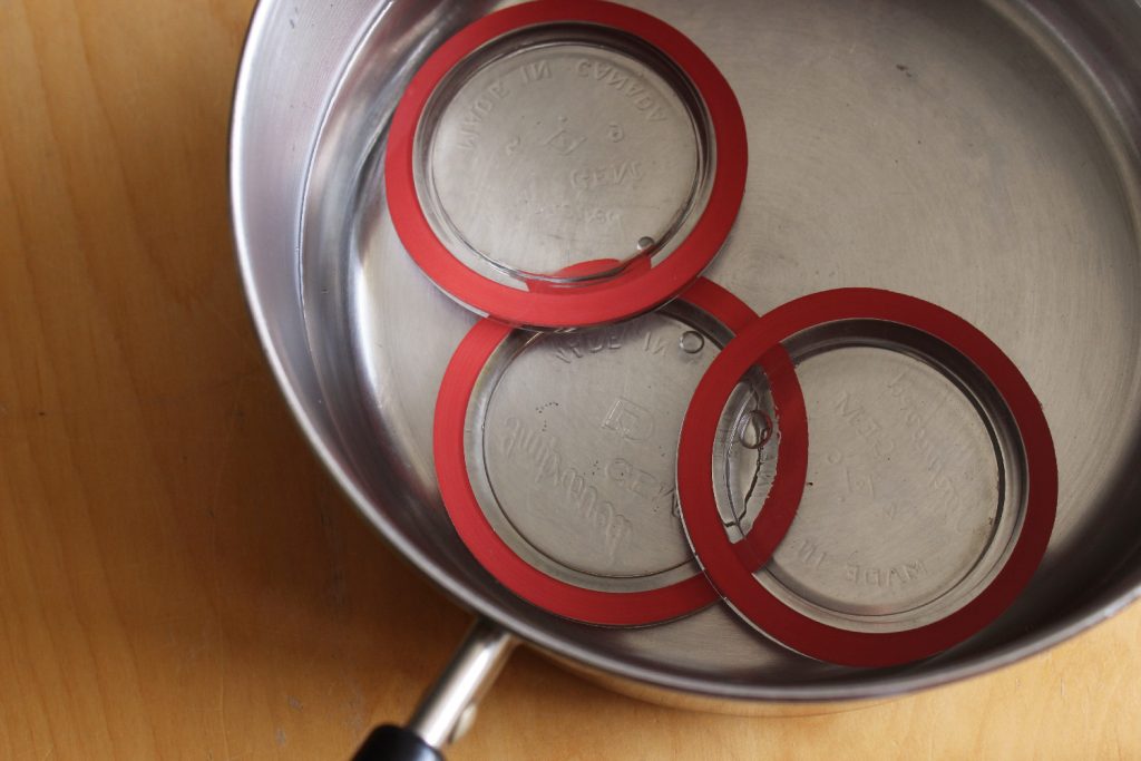 A photo of 78mm antique glass lids with Viceroy rubber gasket rings on them, in a pot, ready to boil.